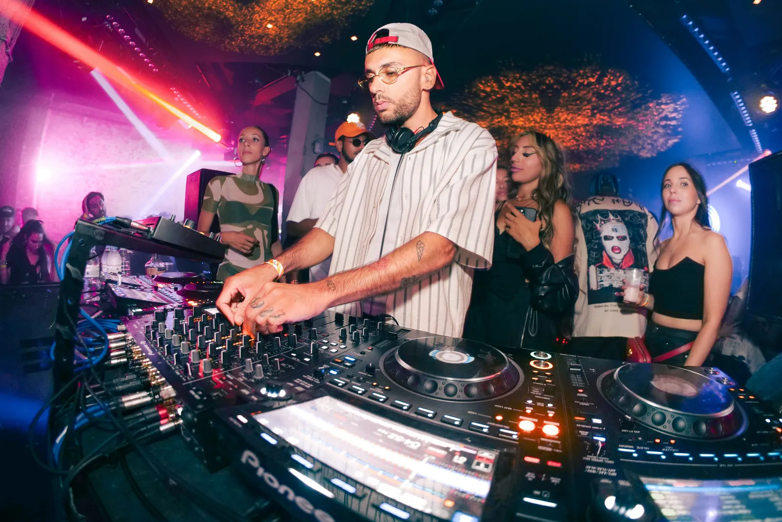 DJ mixar vid DJ-bordet med publik runt sig i rosa scenljus