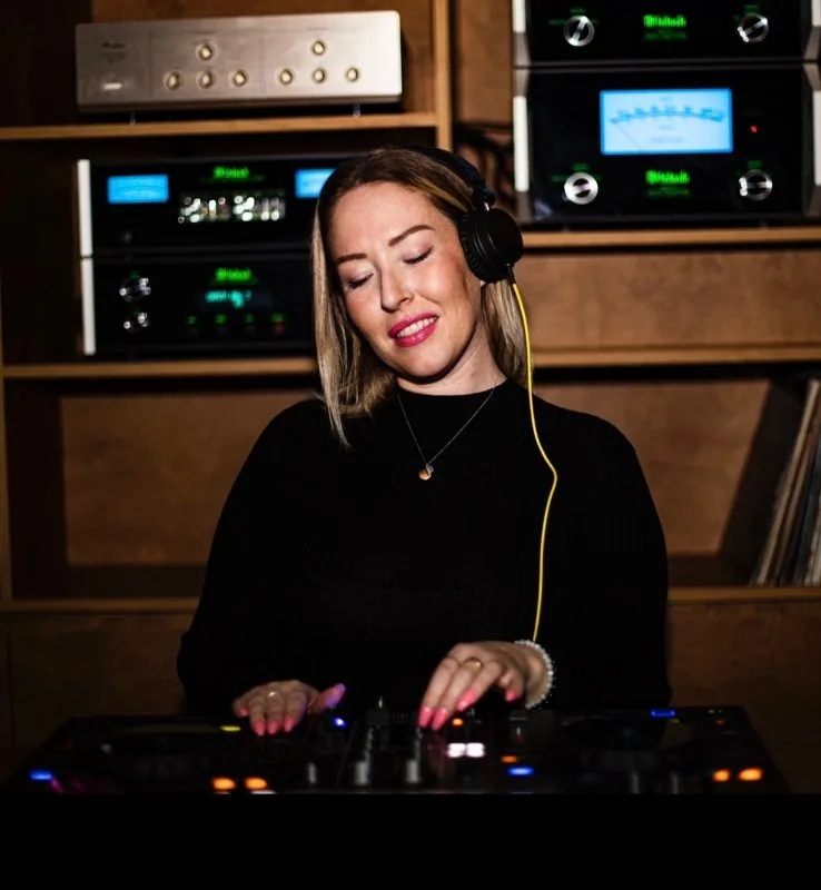 DJ med hörlurar spelar vid ett DJ-bord med tända kontroller