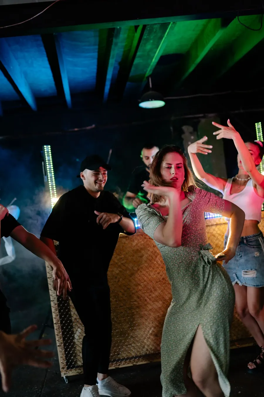 Gæster danser foran DJ-pulten til en fest i farvet lys