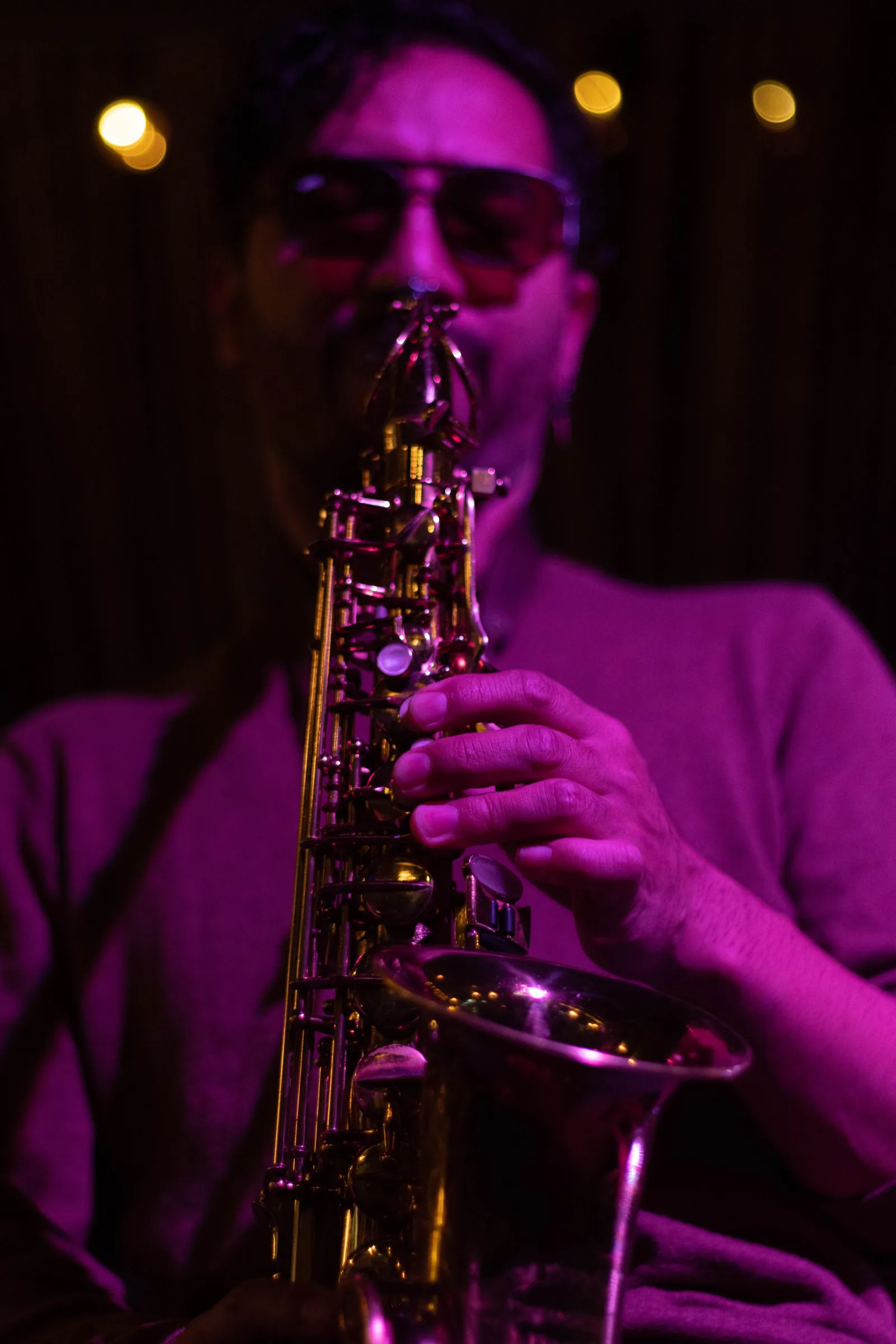 Saxofonist spiller i lilla klublys med dansegulvet bag sig